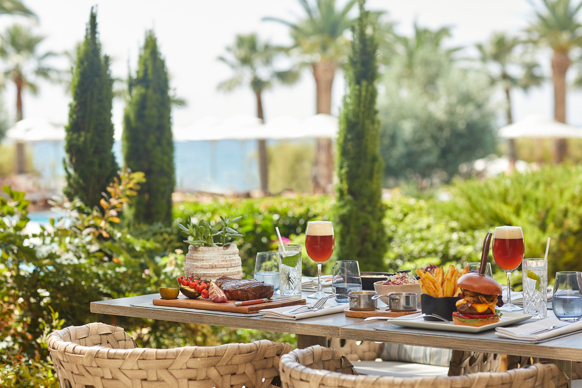 Sani Beach Grill by the Pool, table set with grill plates, hamburger and beer 