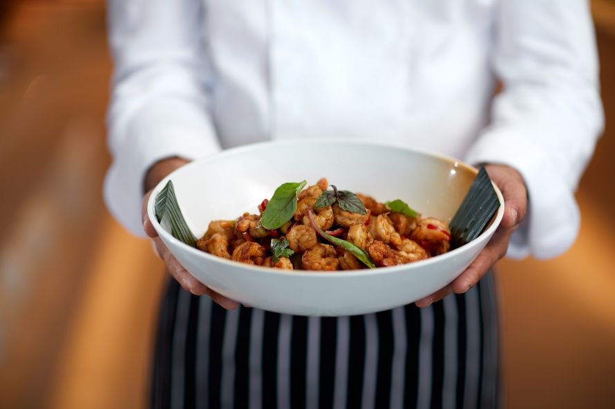 chef holdling plate with chinese food