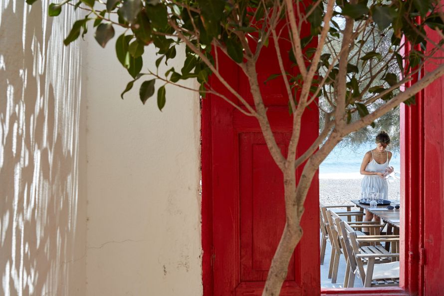 Gaia winery in Santorini, woman preparing table between red doors